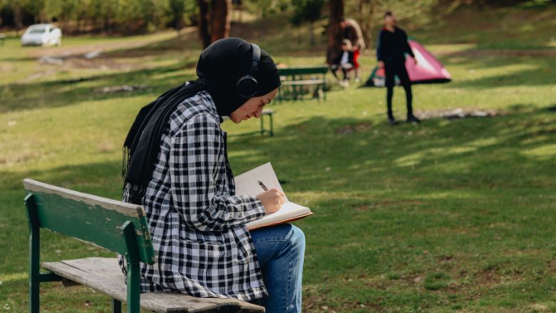 Une femme faisant du journaling dans un parc verdoyant