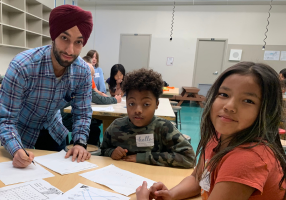 Un tuteur travaille avec deux jeunes apprenants sur une table pendant leur cours de soutien scolaire