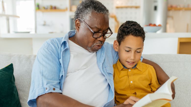 Un grand-père et son petit-enfant lisant un livre ensemble.