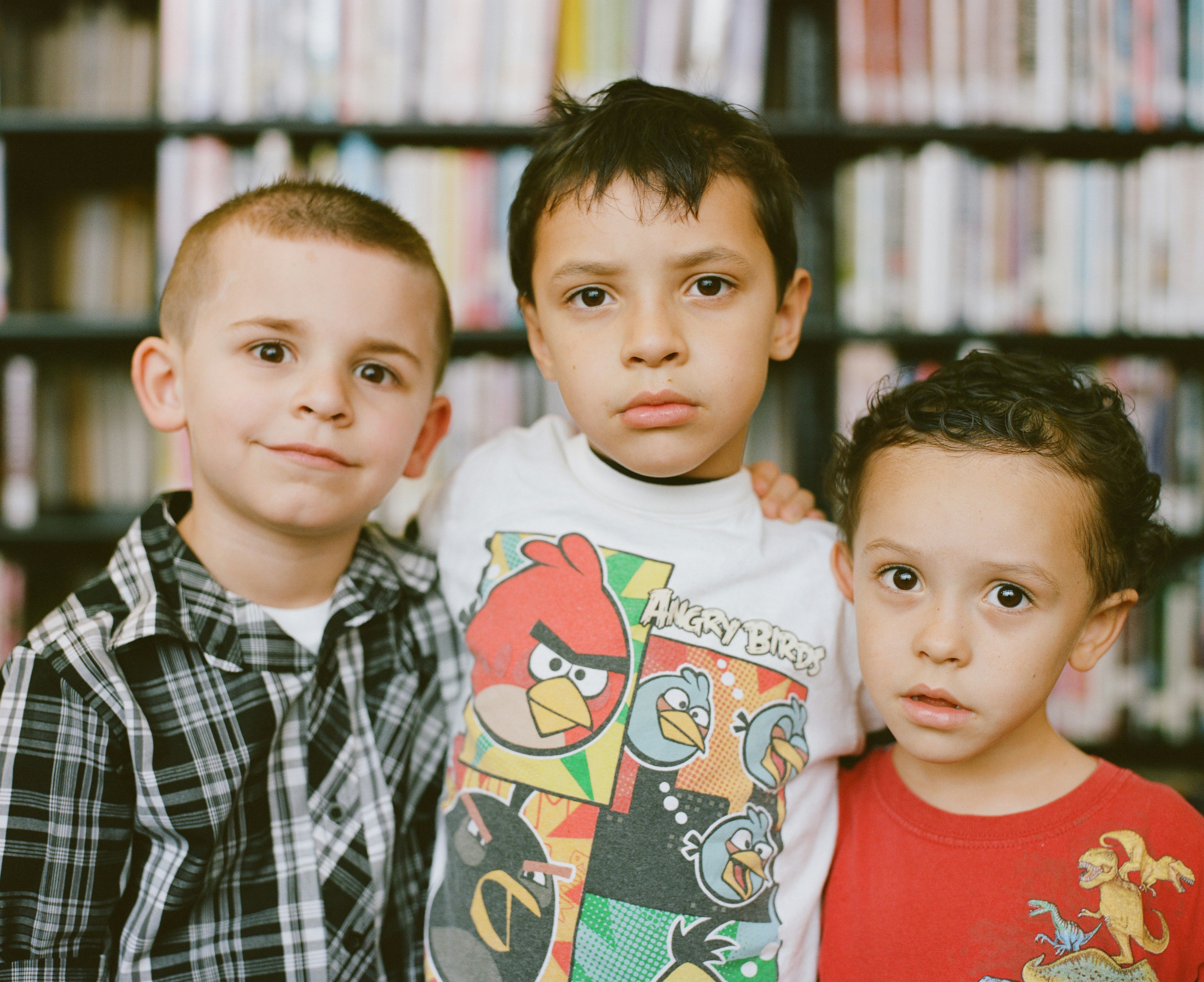 3 enfants regardent la camera dans une bibliothèque