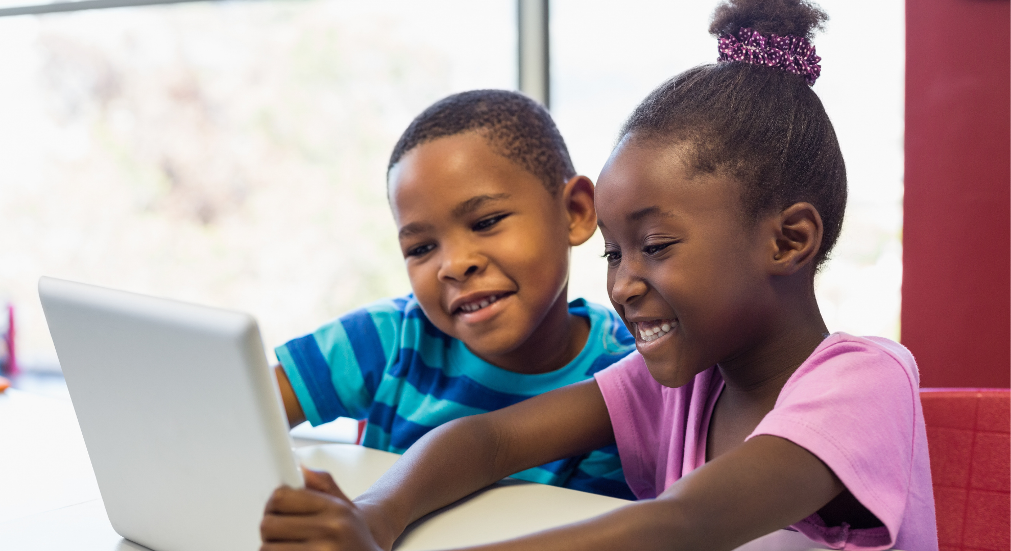 Deux enfants sont en train de lire sur une tablette